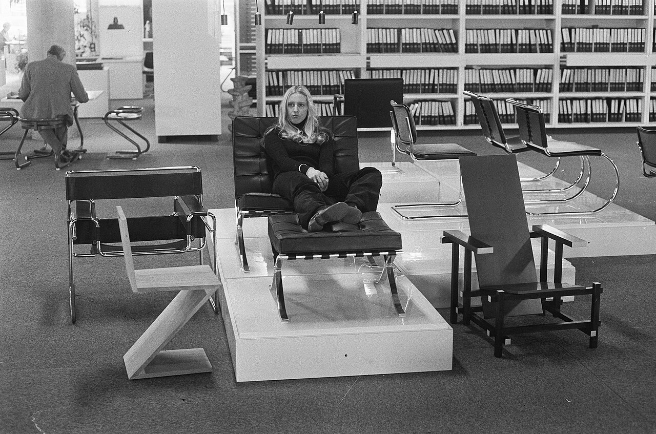 Femme assise dans une chaise Barcelona lors d’une exposition de mobilier moderne en 1973